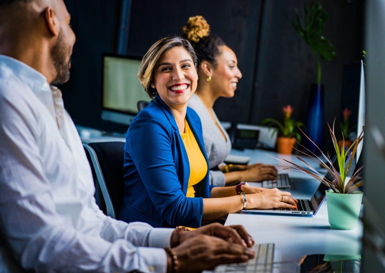 customer support woman smiles at man typing on computer next to her